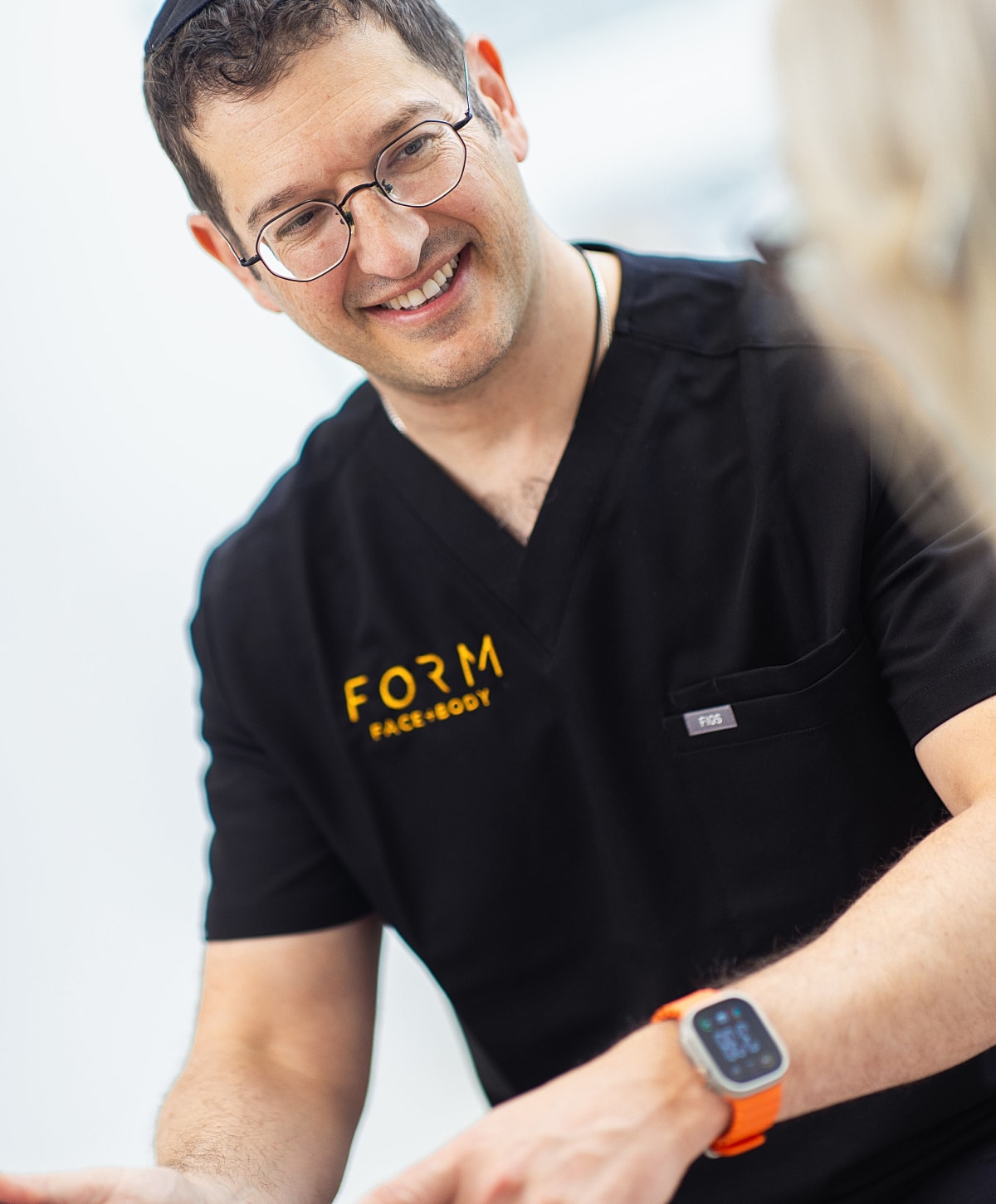 Smiling professional in medical attire, engaged in conversation.