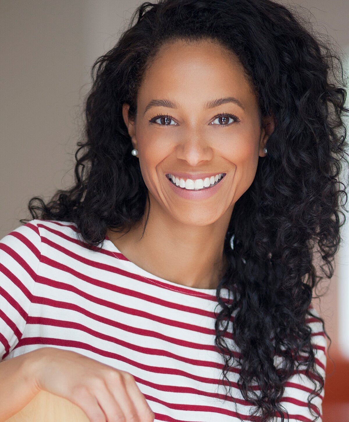 Smiling woman with curly hair in striped shirt.