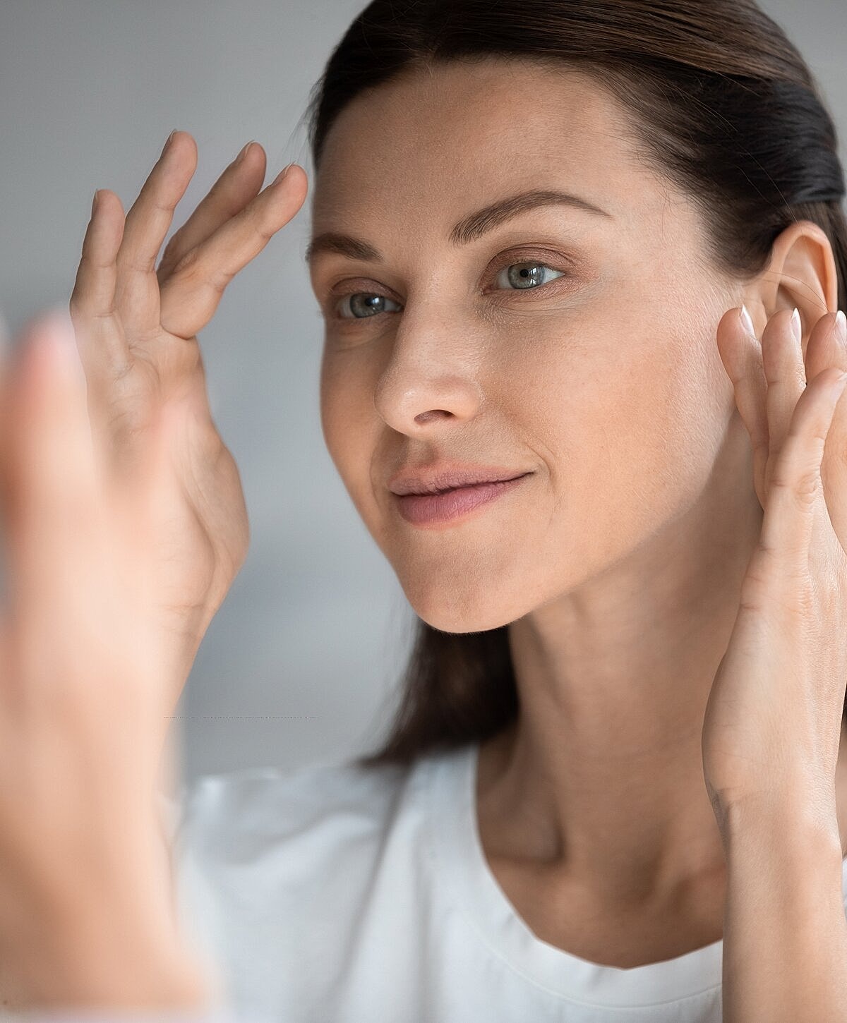 Woman examining her face in the mirror.