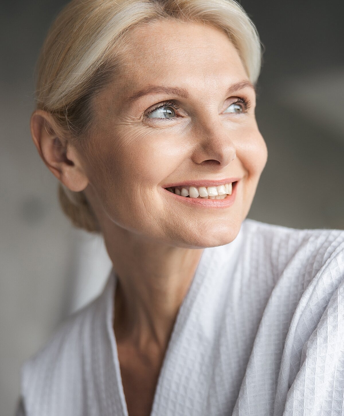 Smiling woman in a bathrobe, soft lighting.