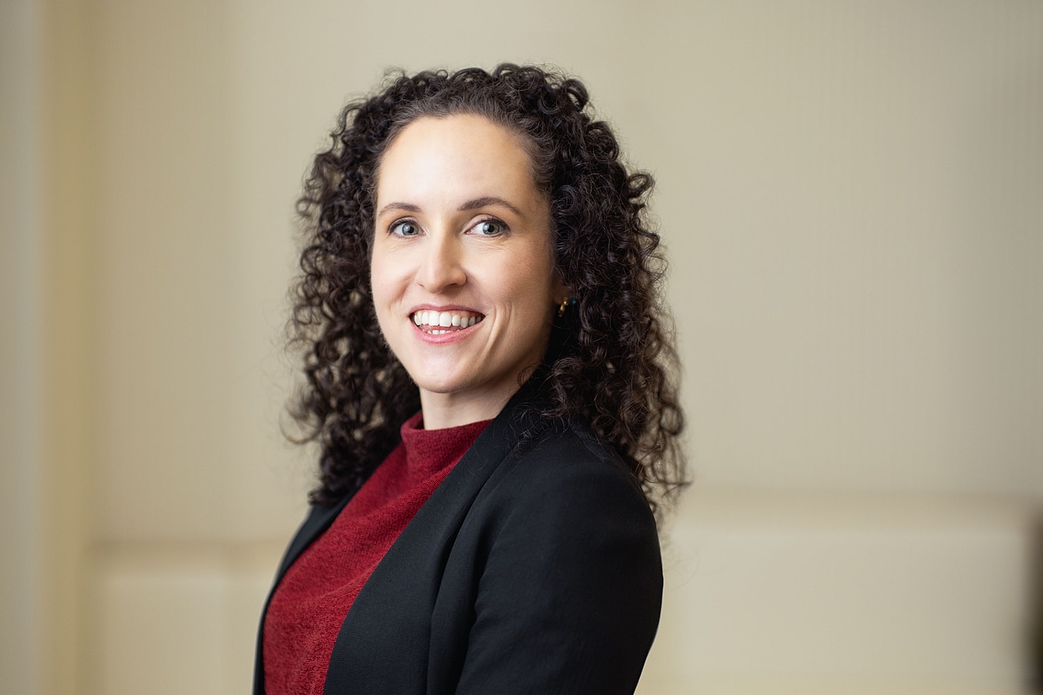 Smiling woman with curly hair in professional attire.