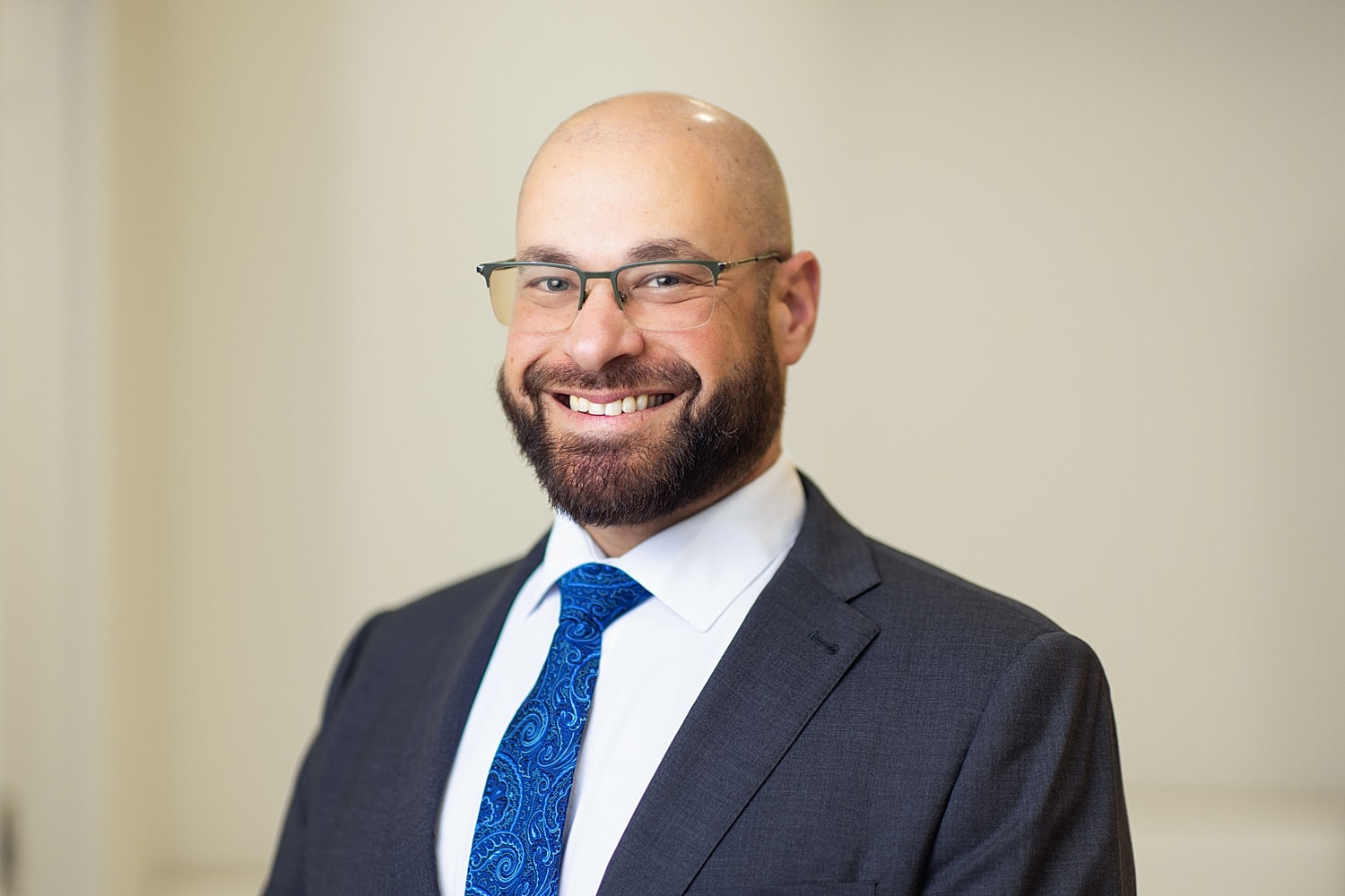 Smiling man in suit with glasses and tie.