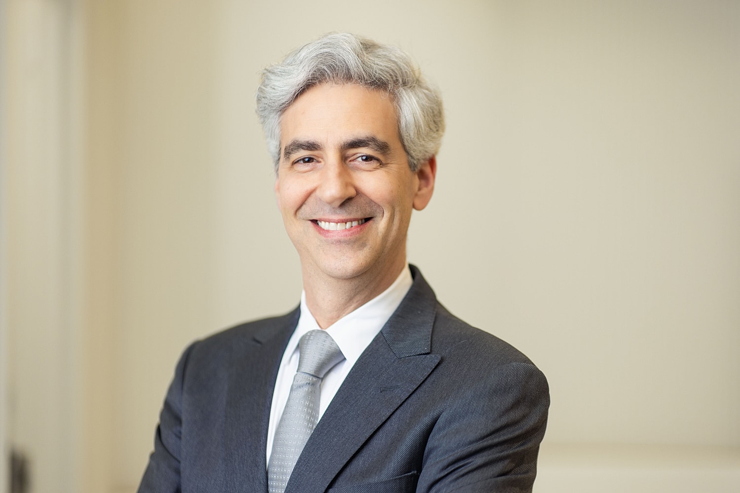 Smiling man in suit with gray hair.