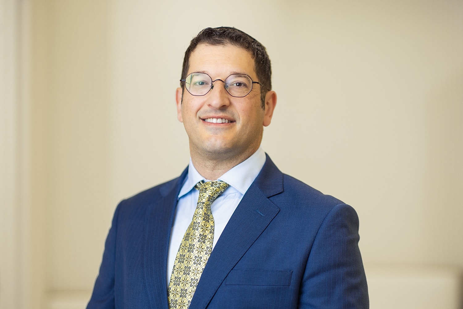 Professional man in suit with glasses smiling.