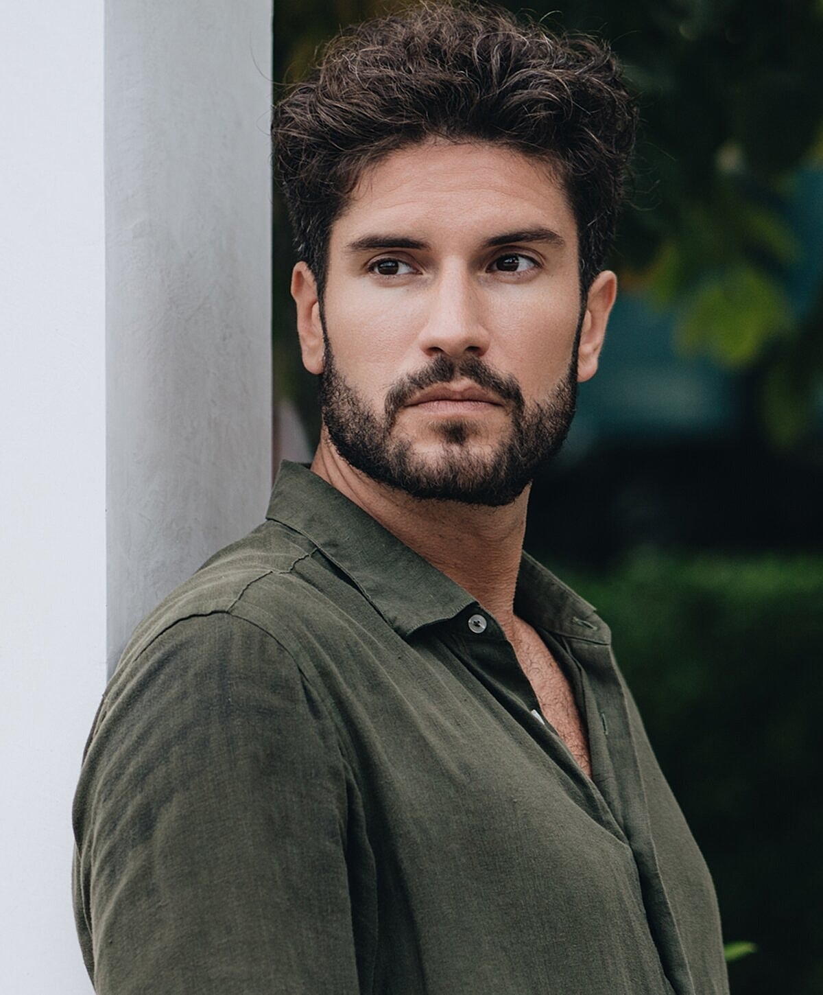 Man with beard wearing green shirt outdoors.