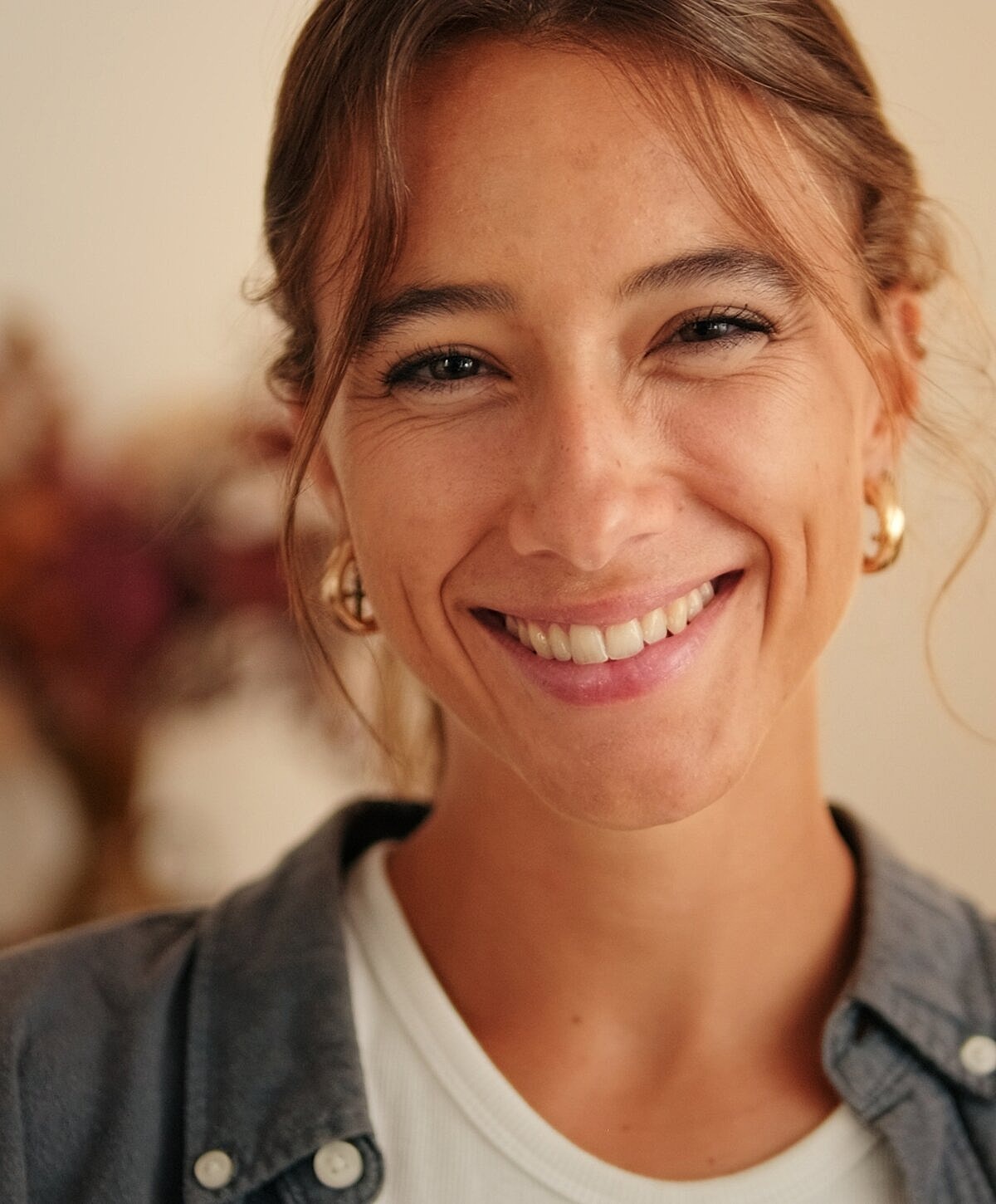 Smiling woman with natural makeup and earrings.