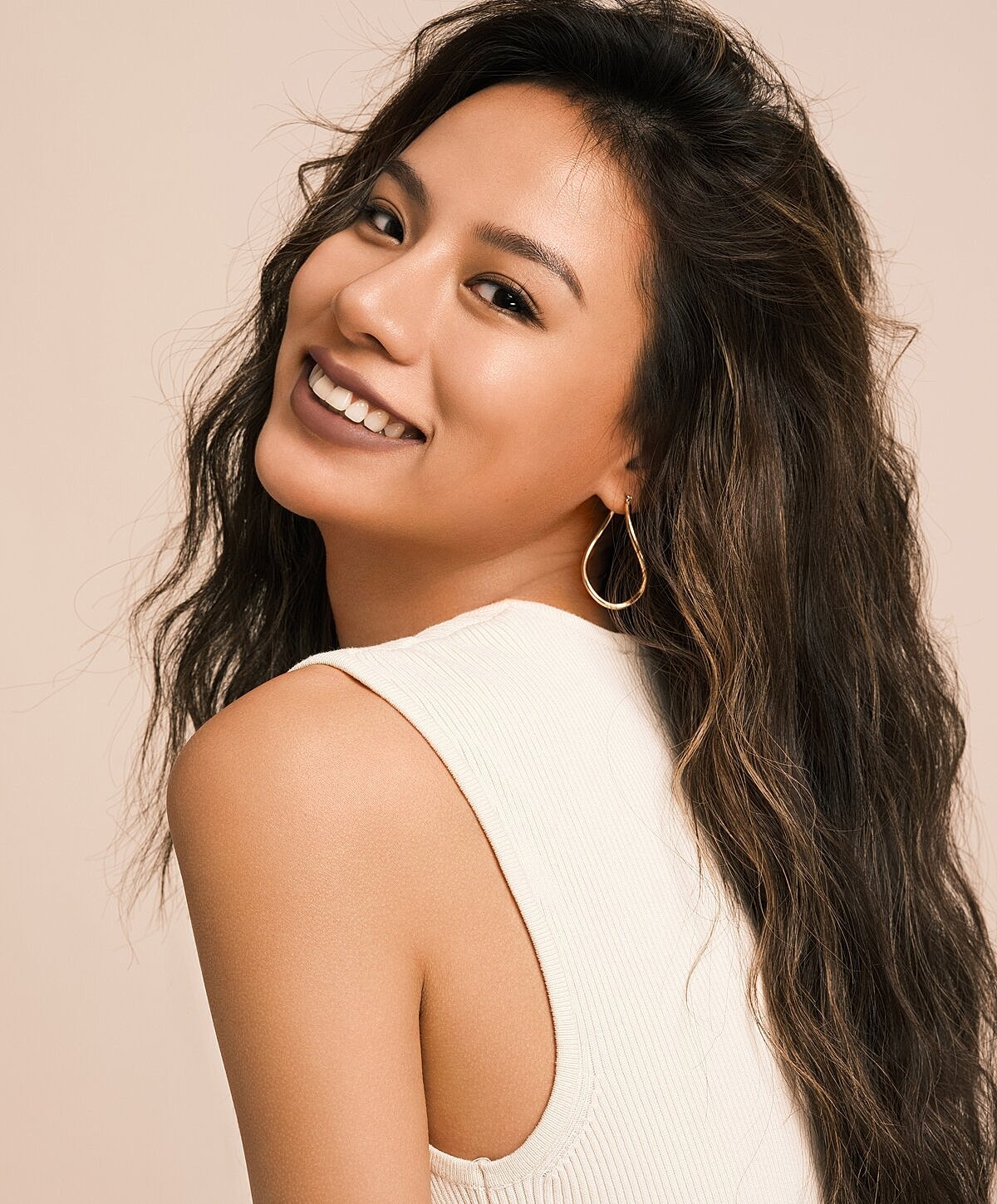 Smiling woman with long, wavy hair and earrings.
