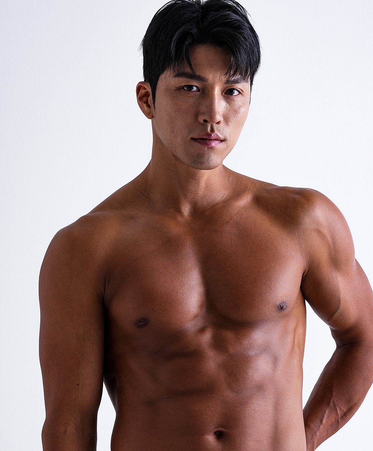 Muscular man with short dark hair, serious expression.