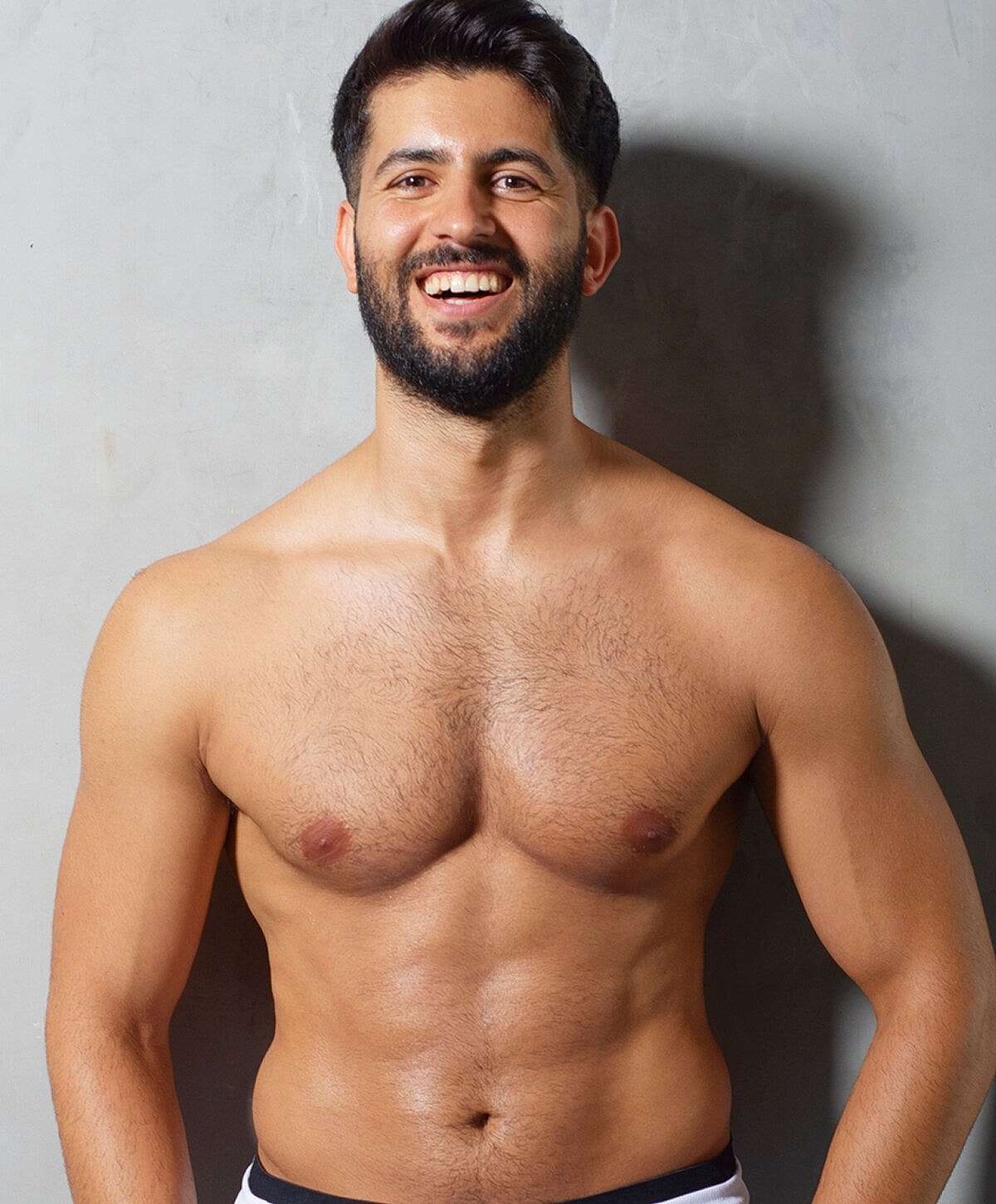 Smiling man with beard posing shirtless.