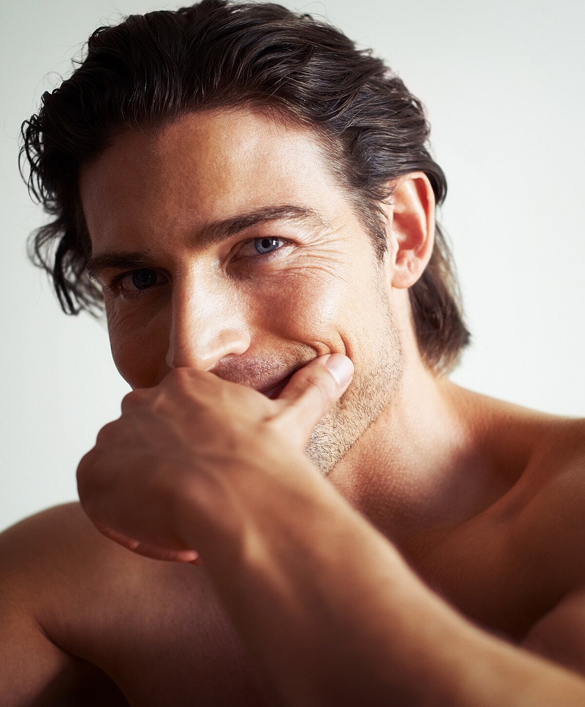 Man smiling with hand near face.