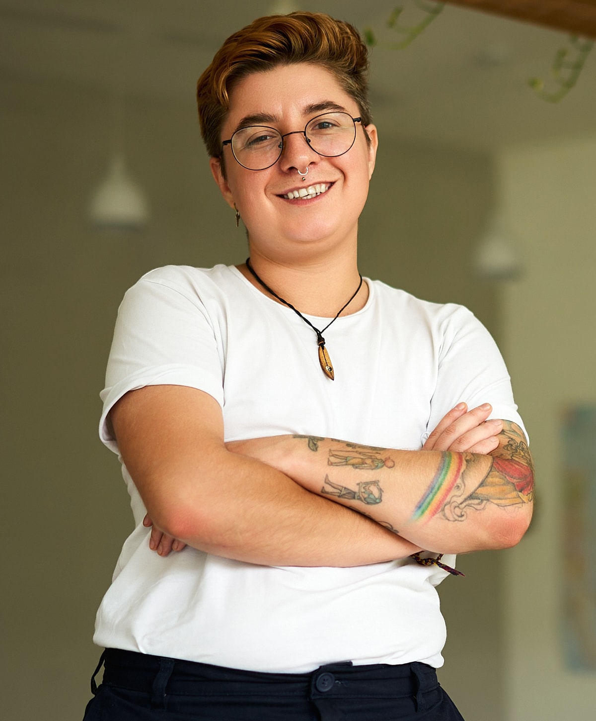 Smiling person with tattoos in casual clothing.