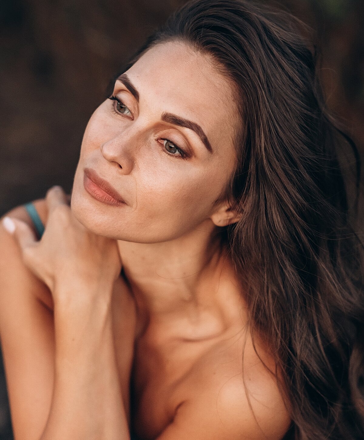 Woman with long hair in soft, thoughtful pose.