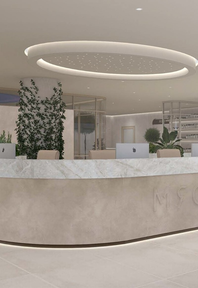Modern reception area with marble counter and plants.