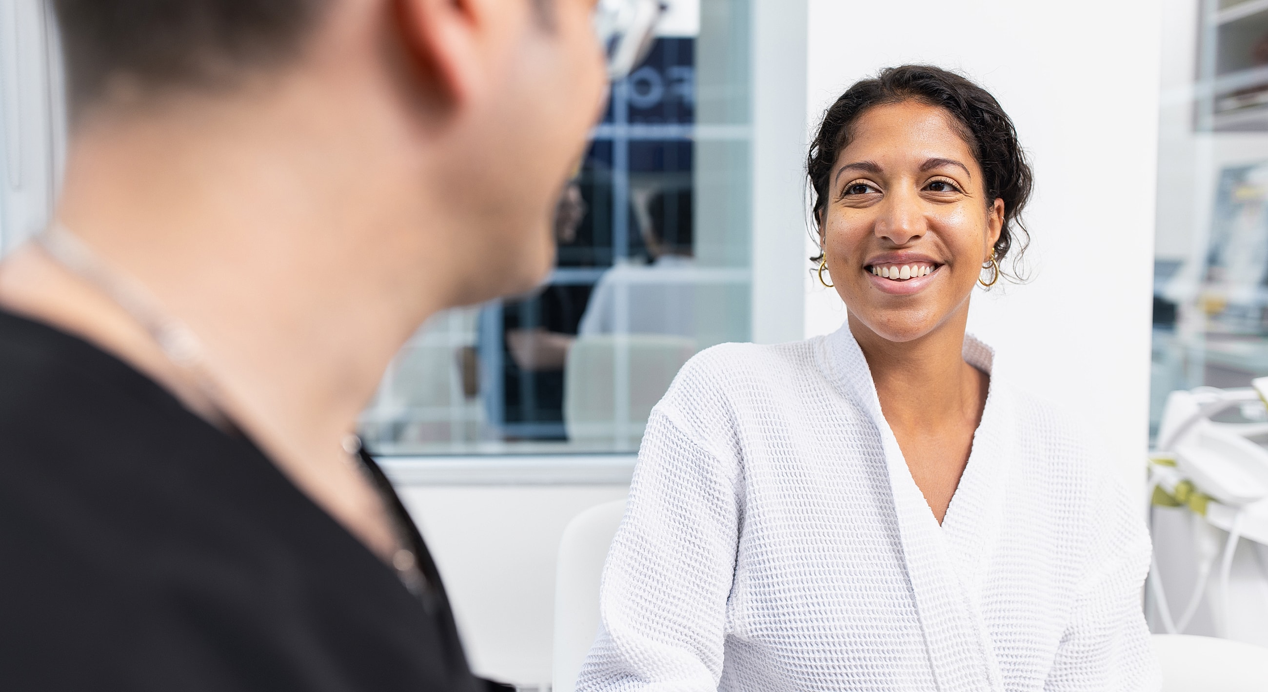 Smiling woman in a clinical consultation setting.