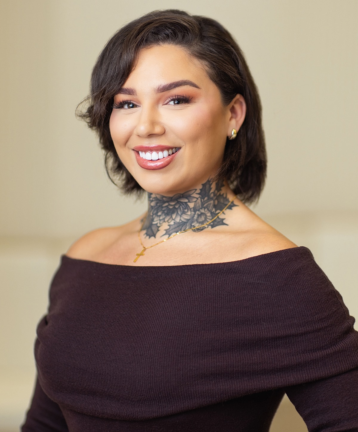 Smiling woman with stylish tattoo and off-shoulder top.