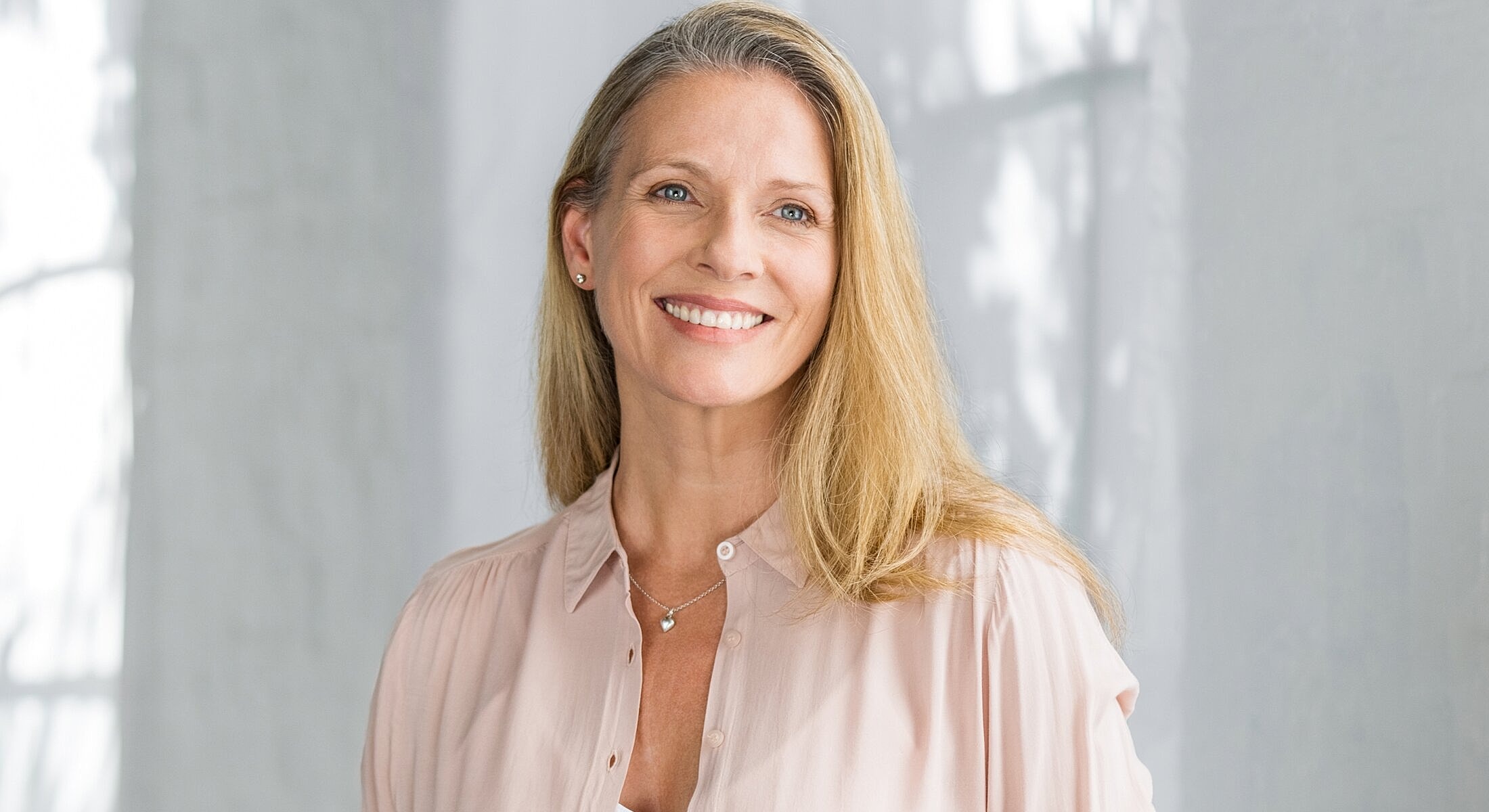 Smiling woman with long hair in soft lighting.