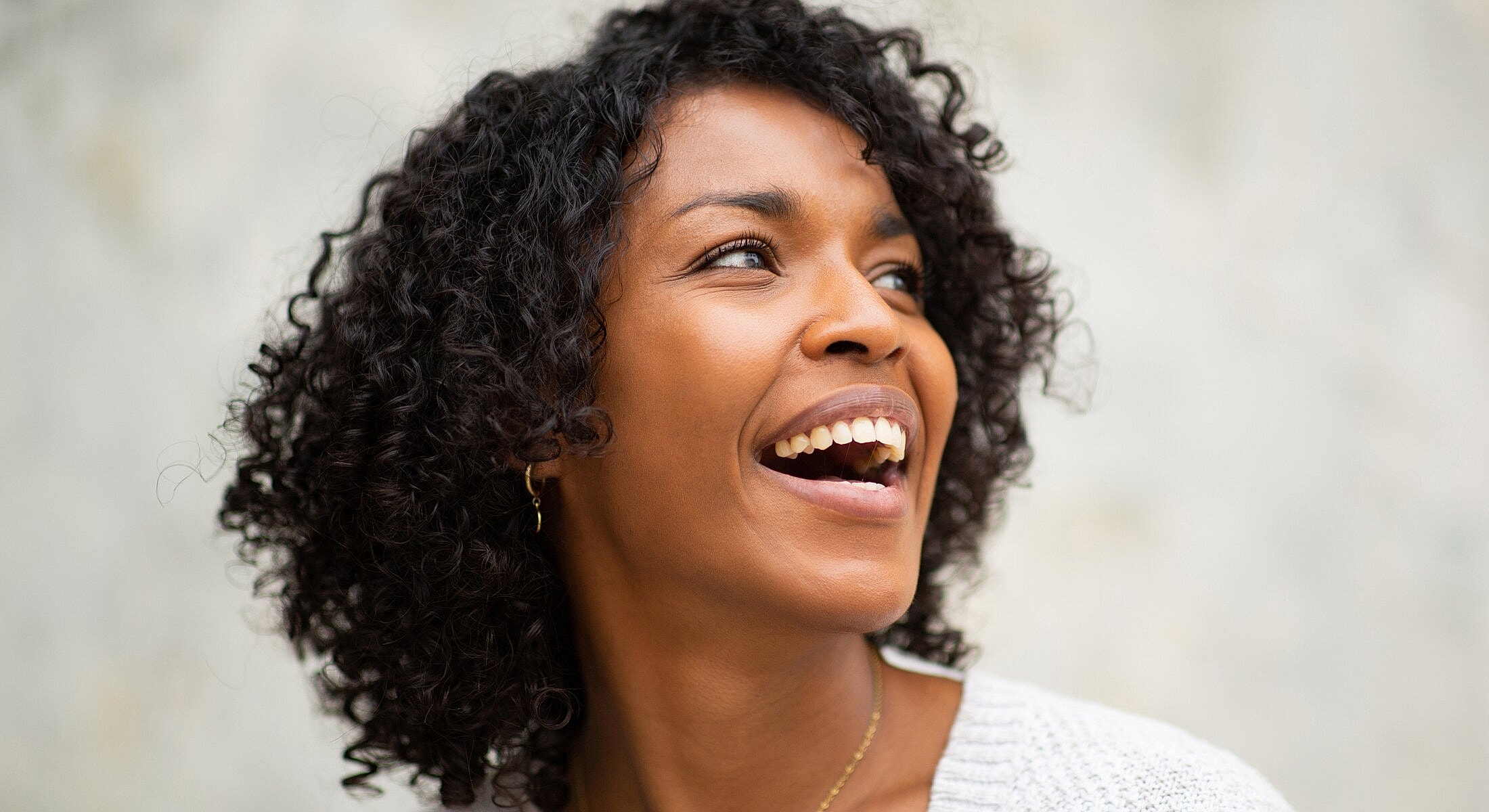 Smiling woman with curly hair and joyful expression.