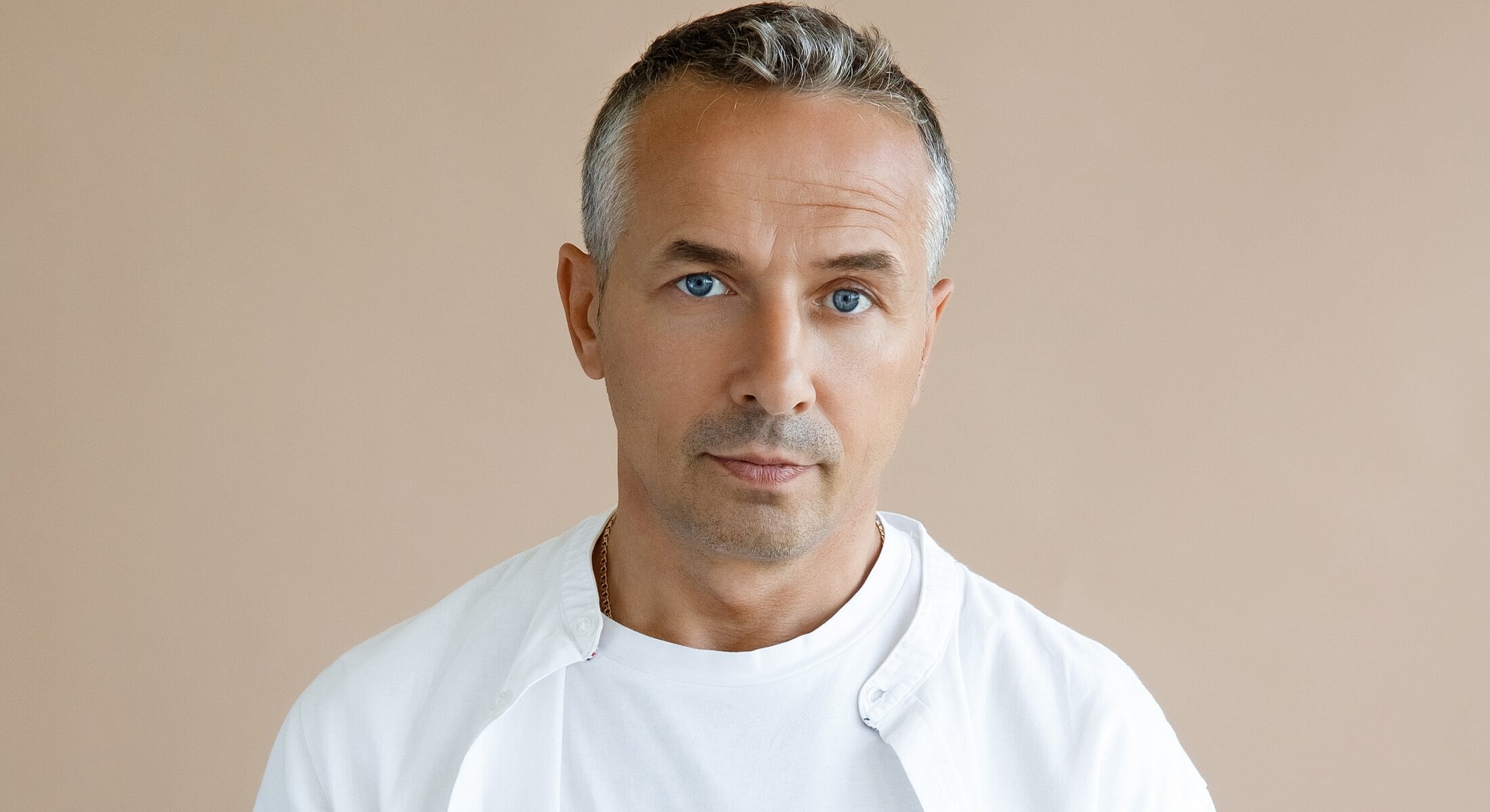 Man with gray hair and blue eyes, studio portrait.