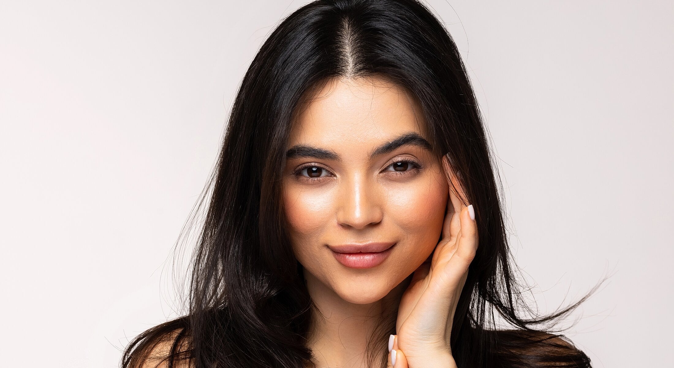 Stylish woman smiling with long, dark hair.