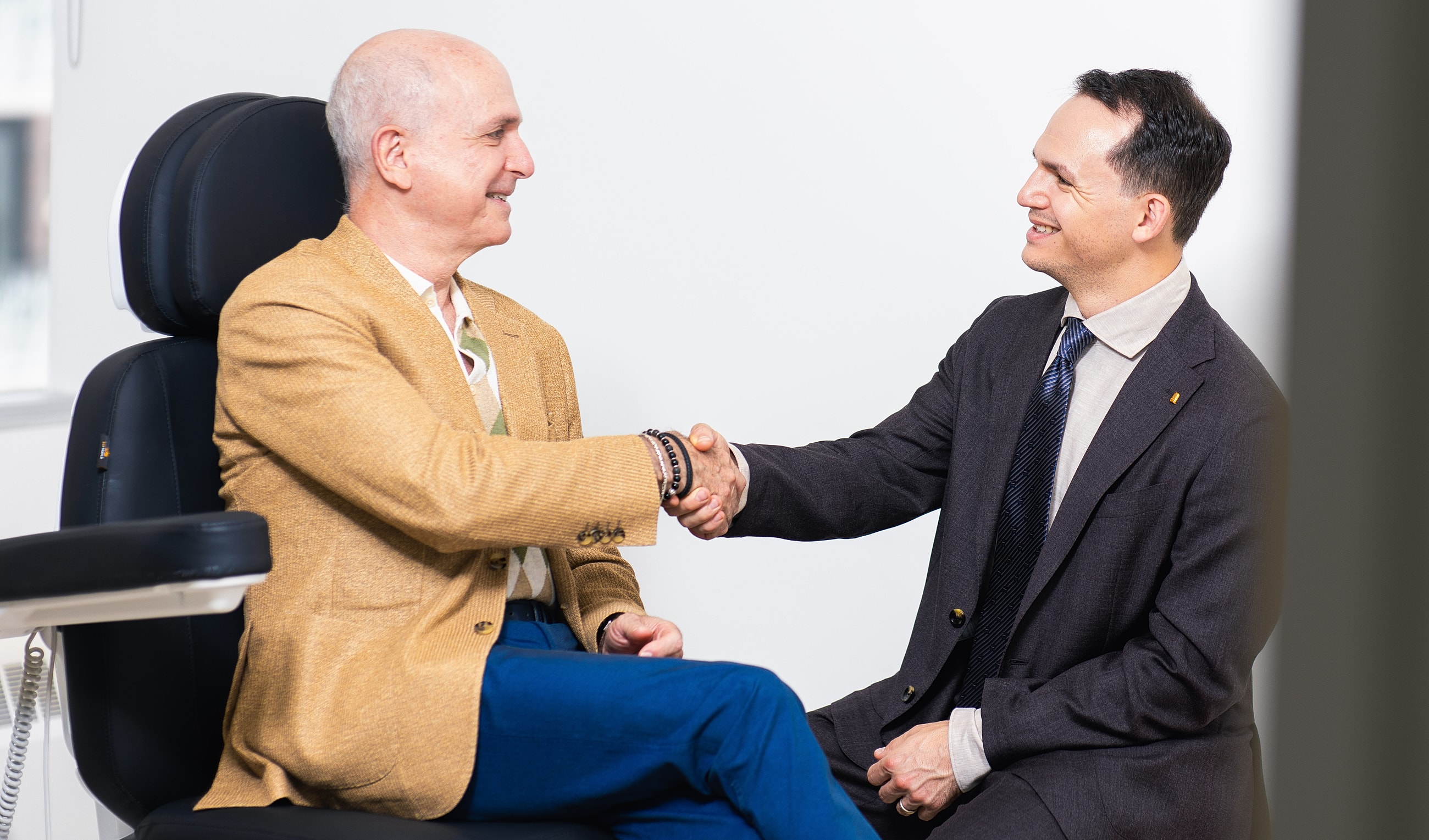 Two men shaking hands in a professional setting.