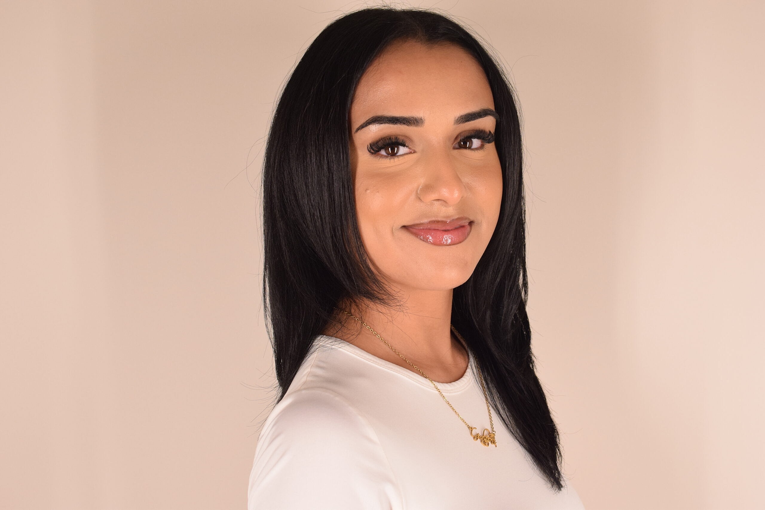 Smiling woman with long black hair and necklace.