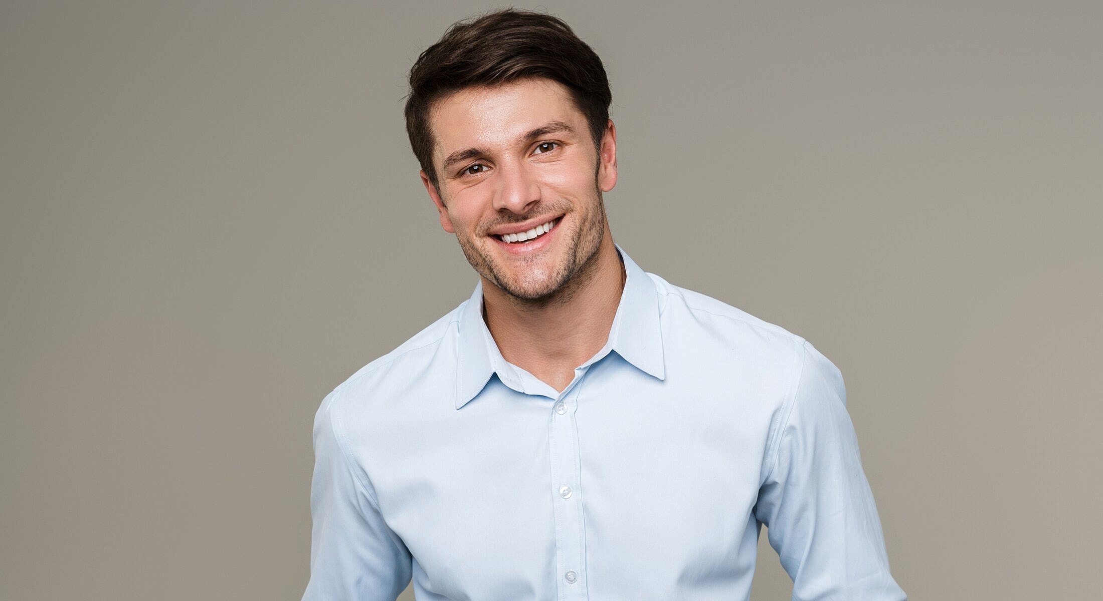 Smiling man in a light blue dress shirt.