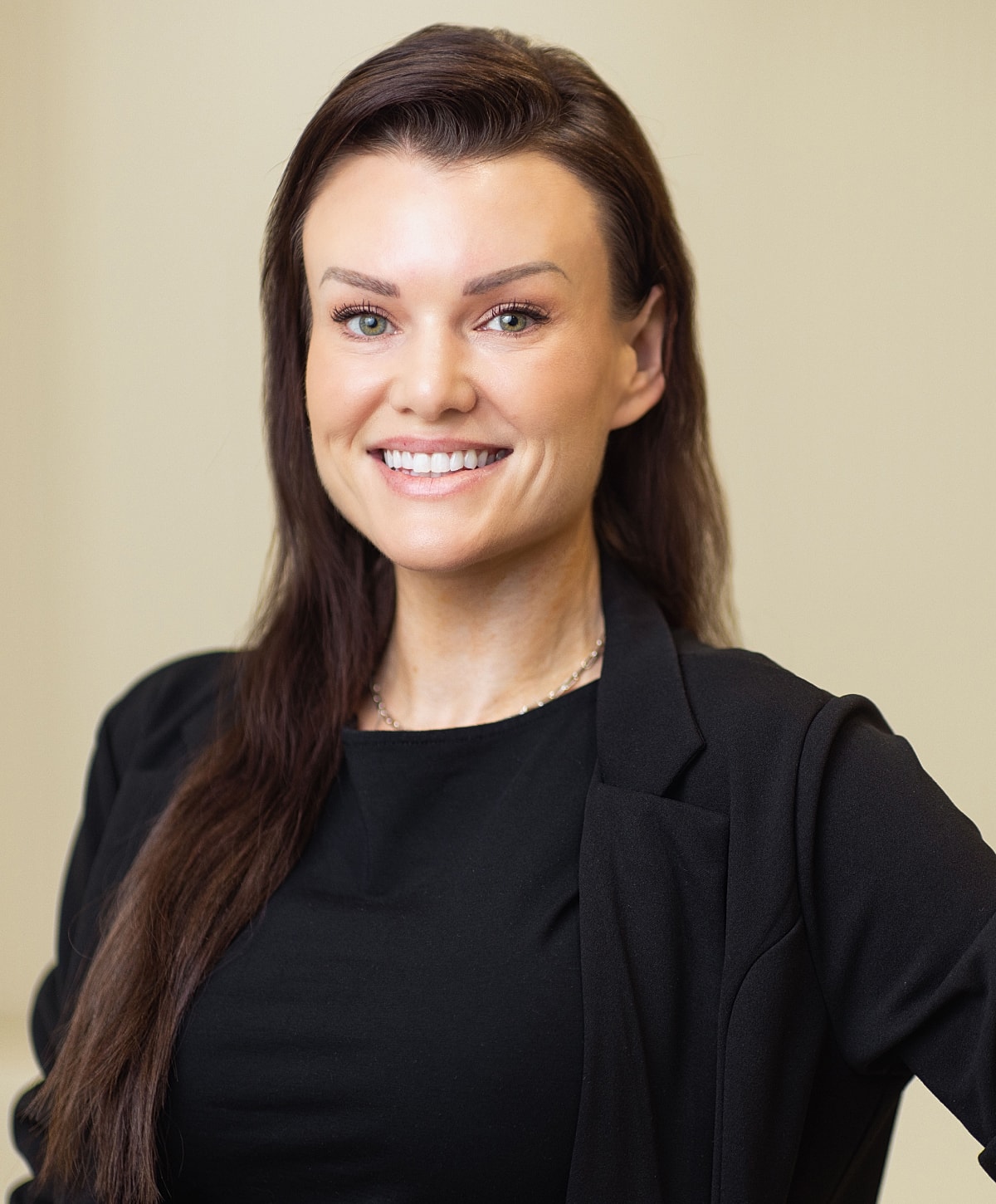Smiling woman in professional attire against neutral background.