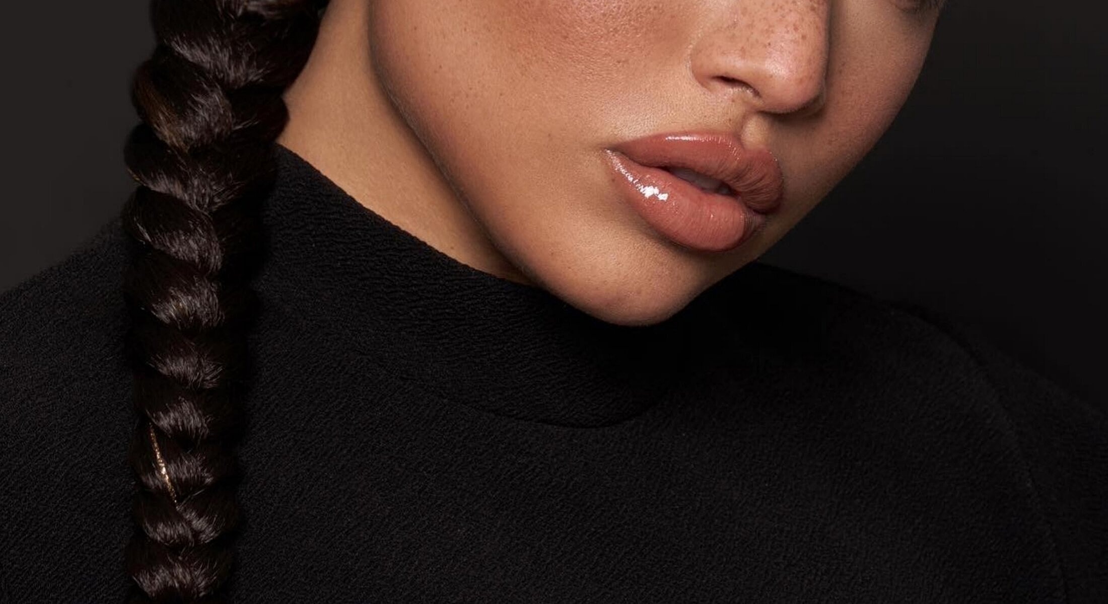 Close-up of braided hair and glossy lips.