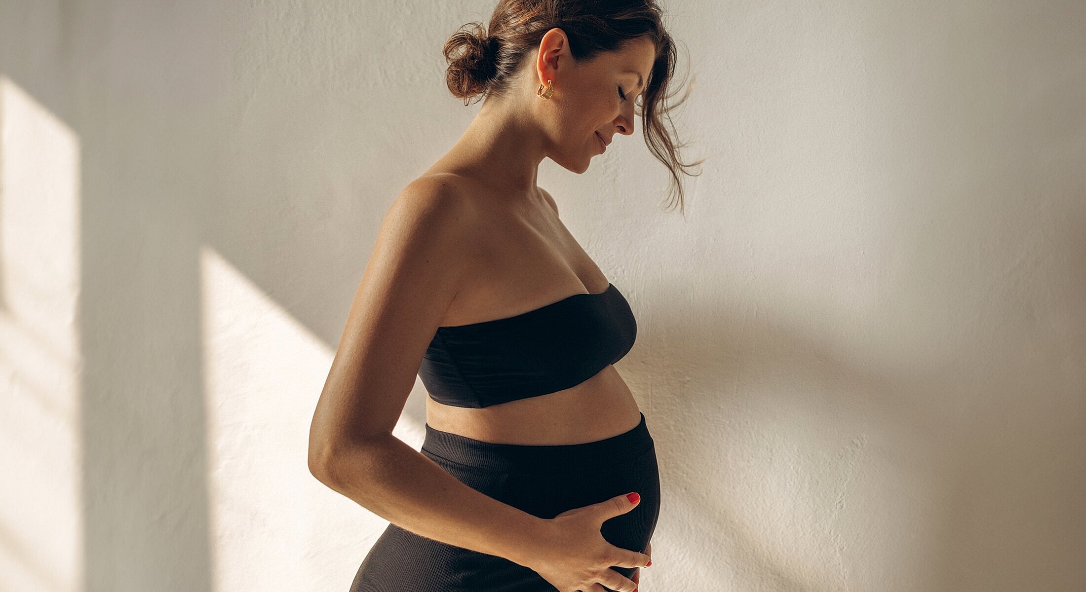 Pregnant woman gently cradling her belly.