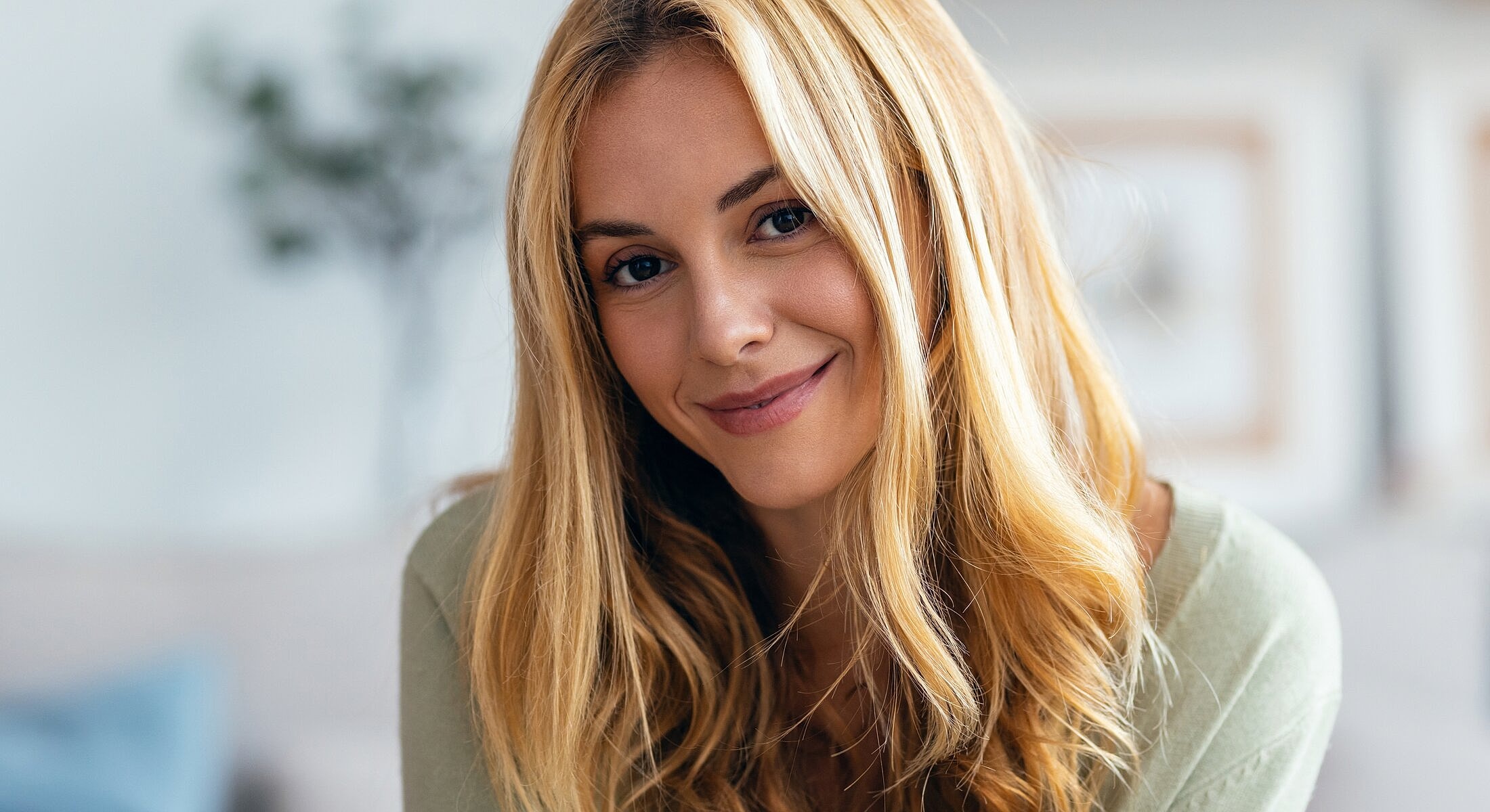 Smiling woman with long blonde hair indoors.