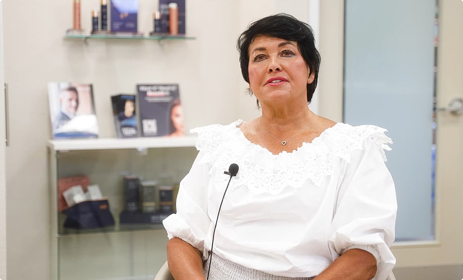 Woman in white blouse speaking in salon.