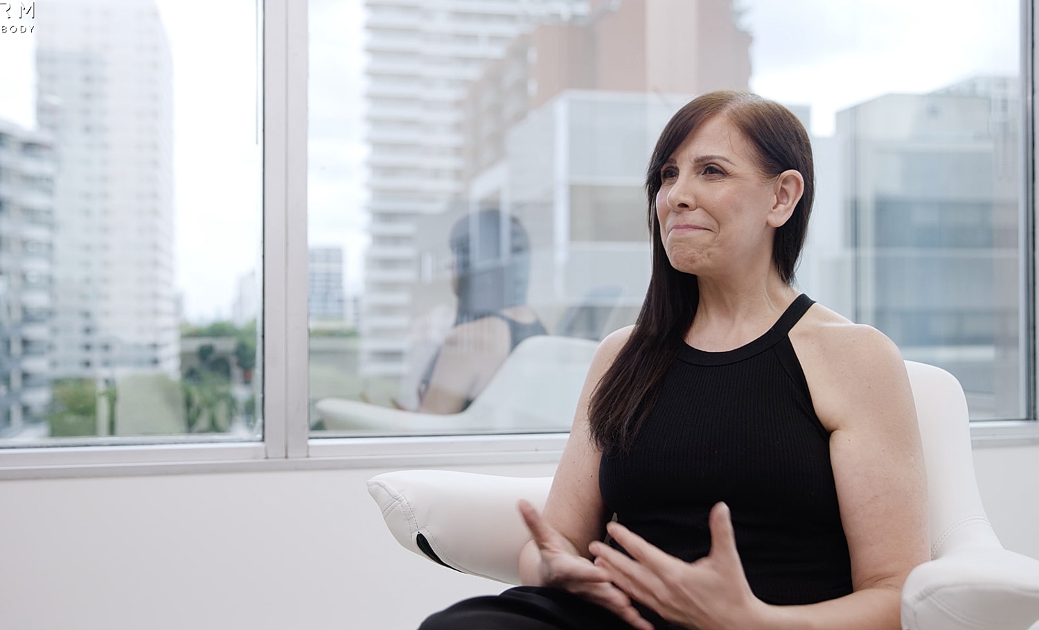 Woman sitting by window, discussing her thoughts.